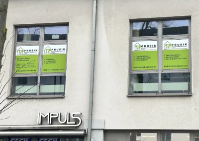 Professionelle Renovierungsservice-GmbH mit grünen Werbeaufklebern an Bürofenstern.